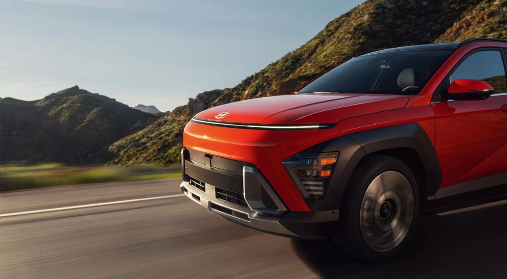 The front end of a red 2025 Hyundai Kona Limited driving on a highway.