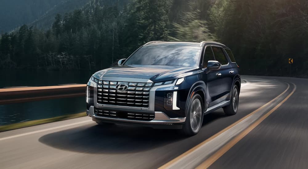 A black 2025 Hyundai Palisade driving down a road.