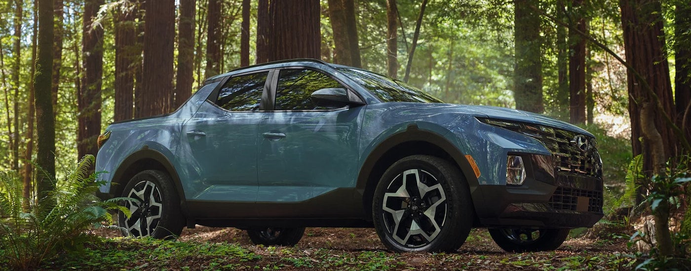 A blue 2024 Hyundai Santa Cruz parked in the woods.
