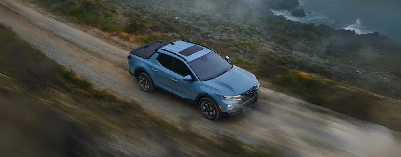 A blue 2022 Hyundai Santa Cruz is shown on a coastal road after visiting a Hyundai dealer in Seekonk.
