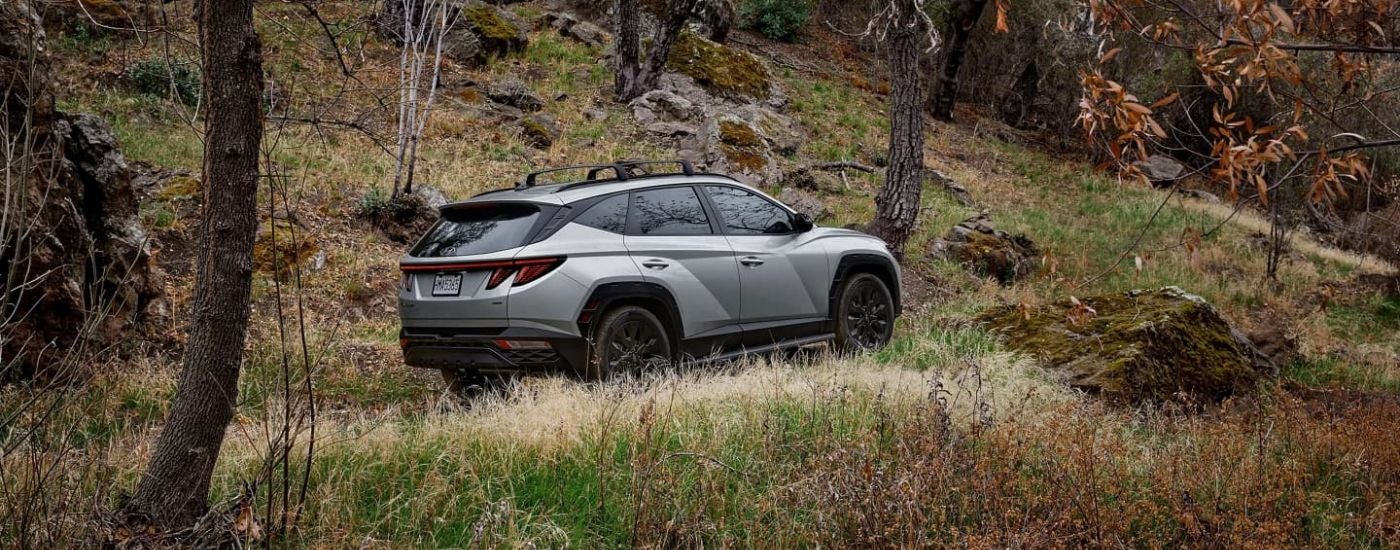 A silver 2023 Hyundai Tucson XRT is shown off-roading on a trail.