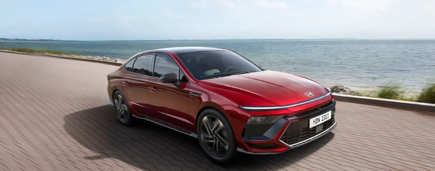 A red 2024 Hyundai Sonata driving down a road.