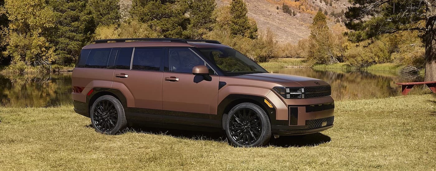 A bronze 2024 Hyundai Santa Fe is shown from the side while parked near a lake.