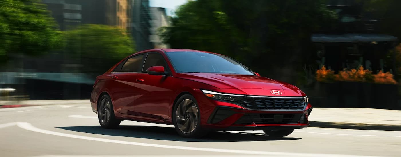 A red 2025 Hyundai Elantra Limited driving on a winding road.