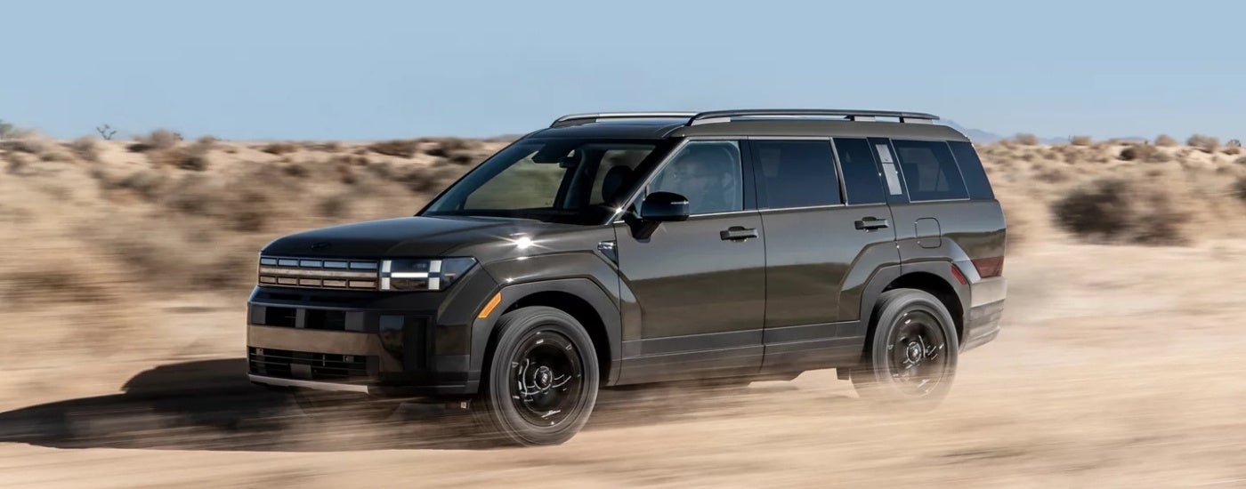 A grey 2024 Hyundai Santa Fe XRT driving on a dusty road.
