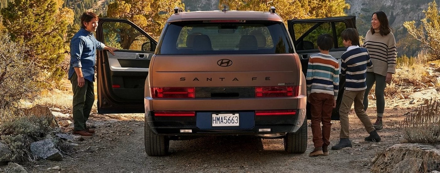 Rear view of a family getting into a copper colored 2025 Hyundai Santa Fe Hybrid.