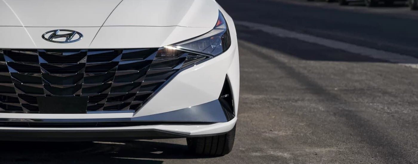 A close-up on the grille and headlights of a white 2021 Hyundai Elantra Hybrid.